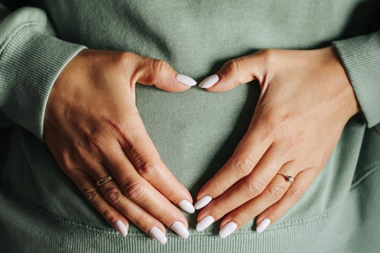 hands over a pregnant stomach in the shape of a heart